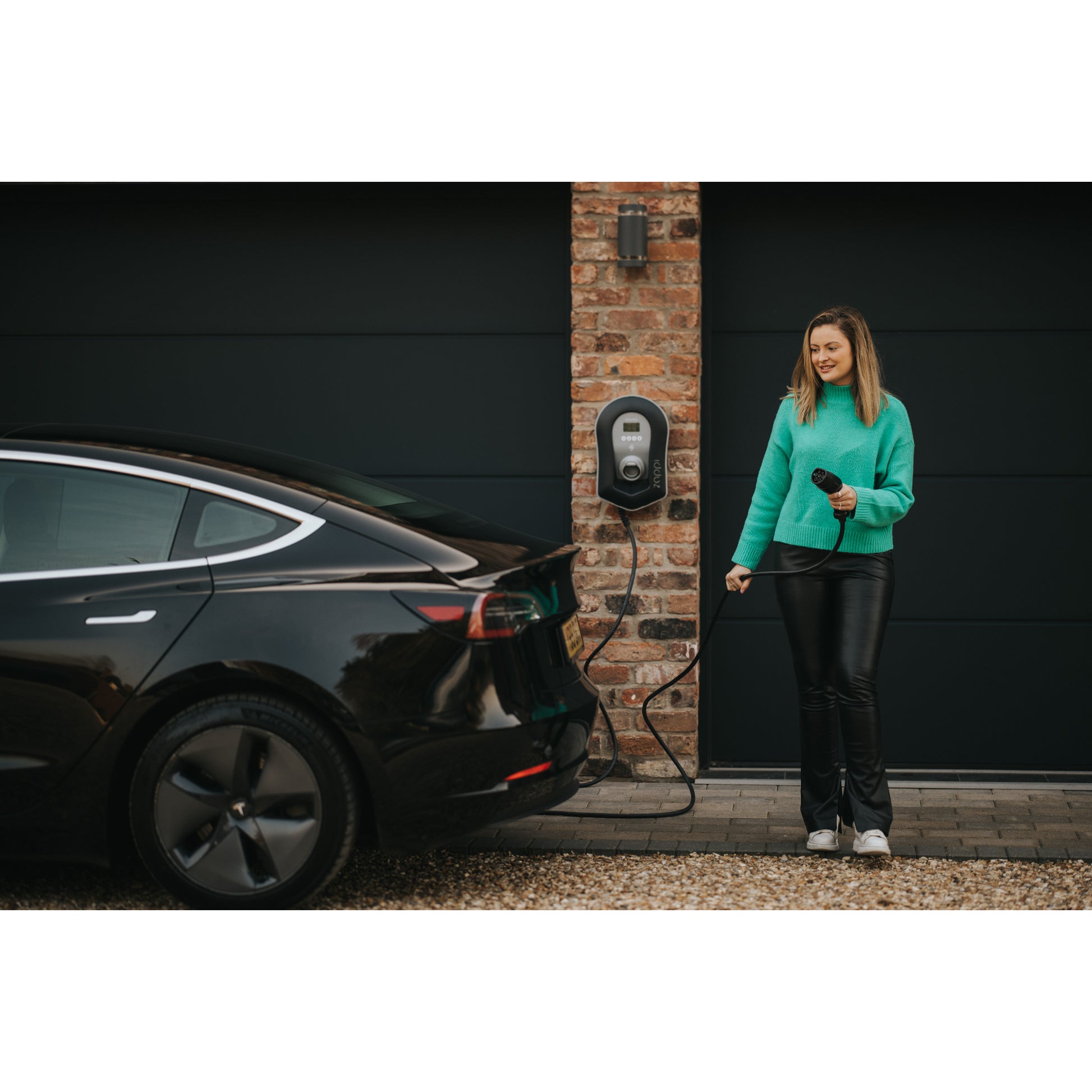 zappi Tethered EV Charger in Black - woman plugging in