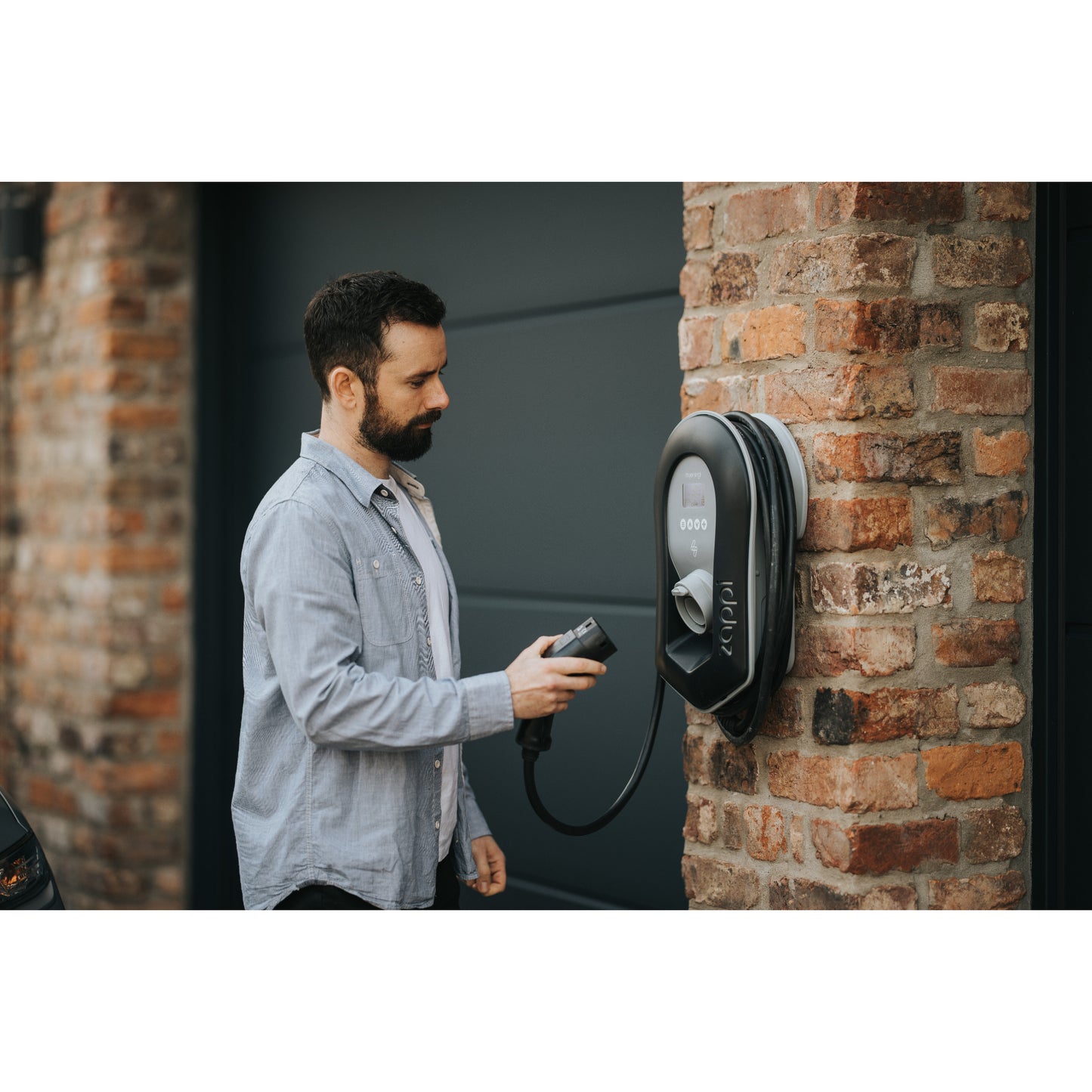 zappi Tethered EV Charger in Black - man plugging in