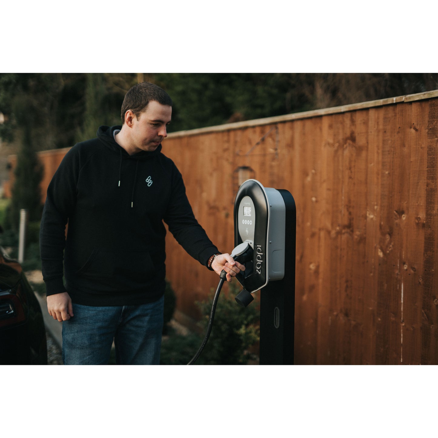 zappi Tethered EV Charger in Black - man plugging in